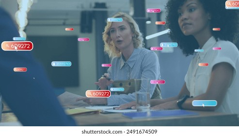 Image of social media icons over caucasian woman talking to diverse colleagues at office. Social media networking and business technology concept - Powered by Shutterstock