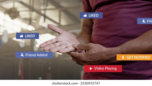 Image of social media notifications over african american man inspecting hand at gym. Fitness, exercise, strength, social networking, digital interface and communication digitally generated image. - Powered by Shutterstock