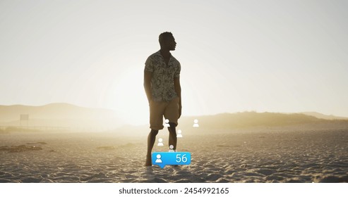 Image of social media reactions over african american man walking on beach at sunset. Holidays, vacations, social media and technology concept digitally generated image. - Powered by Shutterstock