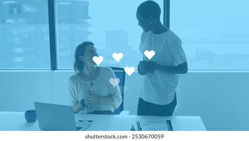 Image of social media reactions over diverse female coworkers in office. Business, social media, communication and technology concept digitally generated image. - Powered by Shutterstock