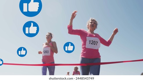 Image of social media thumbs up like symbols, over female runners finishing race. social media, positive feelings and wellbeing concept, digitally generated image. - Powered by Shutterstock