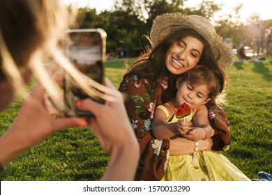 Image Of A Someone Take A Photo By Mobile Phone Of Happy Young Woman Mother With Her Little Daughter Outdoors In Nature Green Park.