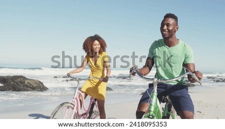 Image of speech bubbles with lol text over happy couple riding bikes on beach. digital interface, social media and global technology concept digitally generated image.