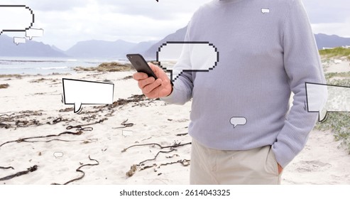 Image of speech bubbles over midsection of caucasian man using smartphone at beach. global connections, social media, technology and digital interface concept digitally generated image.