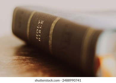 Image of spine of Holy Bible brown leather book. Bible laid on wooden surface. Focusing on the words Holy Bible. 