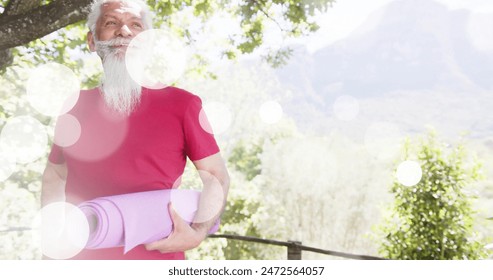 Image of spots of light and trees over biracial senior man with yoga mat in garden. Yoga, senior lifestyle, fitness, active lifestyle and retirement concept digitally generated image. - Powered by Shutterstock