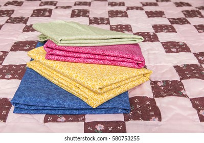 An Image Of A Stack Of Quilt Material In Complimentary Colors On A Nine Patch Quilt.