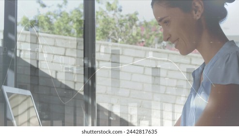 Image of statistics and data processing over woman using laptop. global business, digital interface and technology concept digitally generated image.