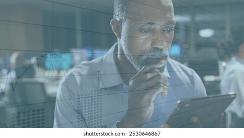 Image of statistics and financial data processing over businessman using tablet. Global business, finance, connections, networks and data processing concept digitally generated image.