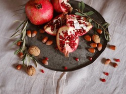 Image Of Still Life With Turkish Pomegranate And Olive Branch On Old Retro Plate. Dark Wood Background, Antique Copper Plate. Fresh Ripe Whole Pomegranates, Opened Pomegranate And Seeds