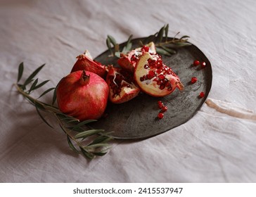 Image of Still Life with Turkish Pomegranate and olive branch on old retro plate. Dark wood background, antique copper plate. Fresh ripe whole pomegranates, opened pomegranate and seeds - Powered by Shutterstock