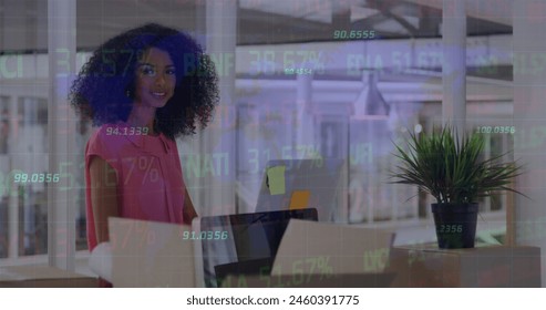 Image of stock market data processing over african american woman using computer at office. Global economy and business technology concept