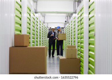 Image of storage room with boxes and two men walking and talking in the background - Shutterstock ID 1635522796