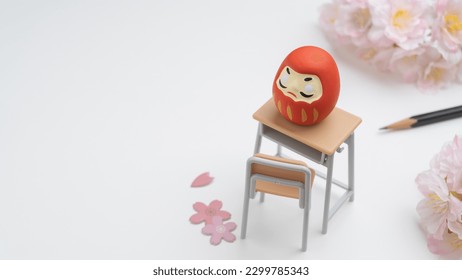 An image of studying for an exam. Cherry blossoms and a study desk and Japanese Daruma dolls.