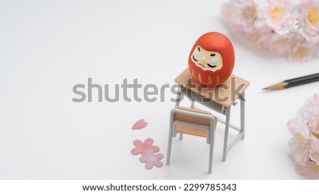 An image of studying for an exam. Cherry blossoms and a study desk and Japanese Daruma dolls.
