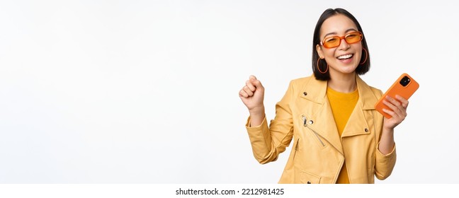 Image Of Stylish Korean Girl Dancing With Smartphone, Laughing Happy And Smiling, Standing Over White Background