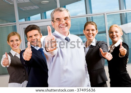 Image of successful business team keeping their thumbs up with senior leader in front smiling at camera