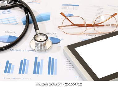 image of tablet, glasses and stethoscope on financial report 