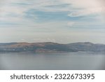 image taken with a telephoto lens of the coast of Galicia, Spain, with its mountains and windmills in the distance, on a day with cloudy sky