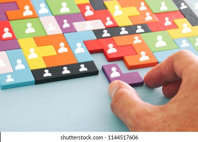 image of tangram puzzle blocks with people icons over wooden table ,human resources and management concept