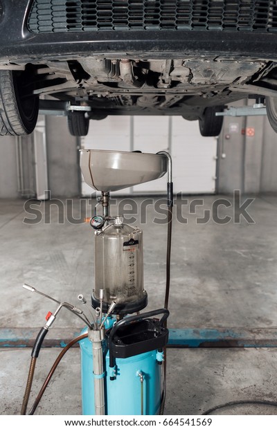 The image of tank for used crankcase oil. the car on\
the lift