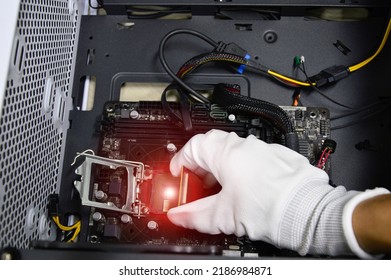 Image of a technician inserting a CPU chip onto a computer motherboard.