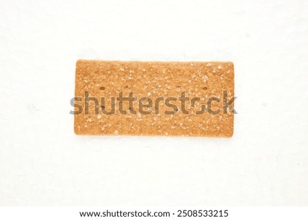 the image of the thin, rectangular coffee biscuit with a sugar coating on a white surface. 