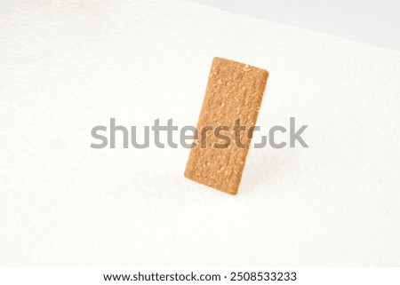 the image of the thin, rectangular coffee biscuit with a sugar coating on a white surface. 