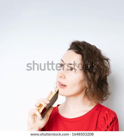 Image of a thinking dreaming young beautiful woman thinks about text messaging on a mobile phone while thinking what to say. isolated over white background