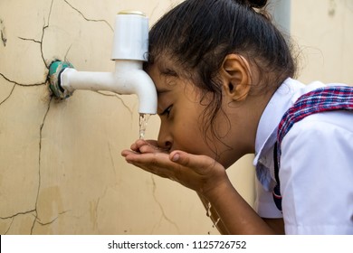 Image Of A Thirsty School Girl Drinking Water From A Tap