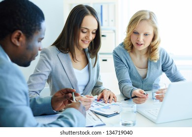 Image of three business partners discussing documents at meeting