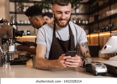 Image Of Three Happy Coffee Men Colleagues In Cafe Bar Working Indoors Using Mobile Phone.