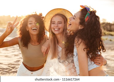 Image of three joyous multiethnic girls 20s in stylish clothing laughing and showing peace sign at camera during beach party at seaside - Powered by Shutterstock