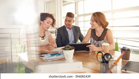 Image Of Three Succesful Business People Using A Tablet During At Meeting