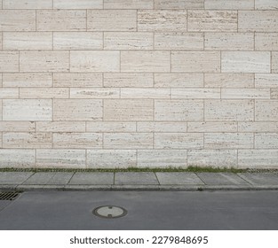 image of a tiled beige stone wall a sidewalk and a street as background, natural stone wall texture as background. Close-up of a wall clad in limestone - Powered by Shutterstock