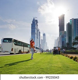 The image of tourists taking pictures of skyscrapers, many of which are still under construction. The whole street is filled with tourist buses in the afternoon.