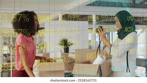 Image of trading board over multiracial coworkers unpacking office supplies on desk. Digital composite, multiple exposure, stock market, teamwork, investment, happy and technology concept. - Powered by Shutterstock