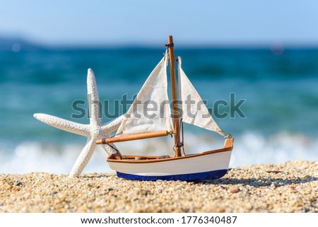 Image of tropical sandy beach and sailboat toy. Summer concept