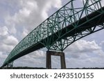 Image of a truss bridge and bright blue sky taken from the river below.