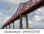 Image of a truss bridge and bright blue sky taken from the river below.