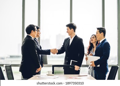 Image Two Asian Business Partners Successful Handshake Together In Front Of Group Teamwork Casual Business Clapping Hands Winning Success Agreement In Modern Office.Partnership Approval And Teamwork 