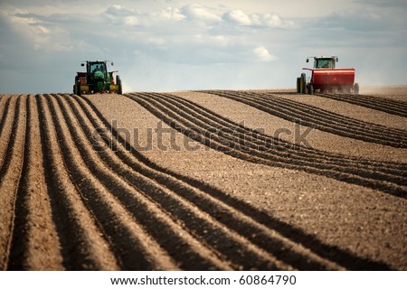 Image of two Tractors planting potatoes in the fertile farm fields of Idaho.