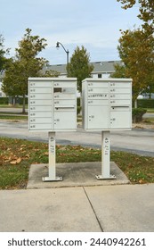 Image of two white community mailboxes lined up on the edge of a street, surrounded by trees and houses, capturing the essence of a quiet and orderly suburban neighborhood.
