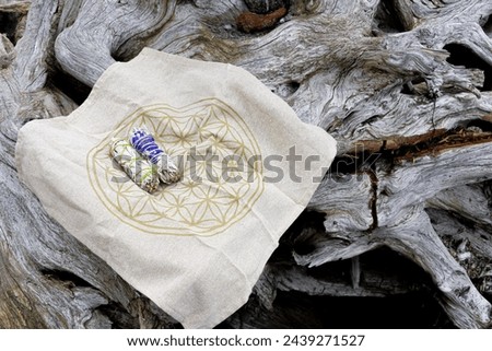 An image of two white sage smudge stick on a flower of life sacred geometry grid cloth. 