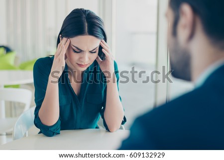 Image of two workers at a meeting in a restaurant. Young pretty exhausted businesswoman having headache because of problems at work.