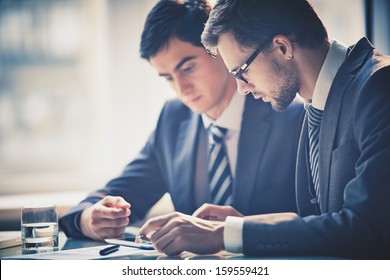 Image Of Two Young Businessmen Using Touchpad At Meeting