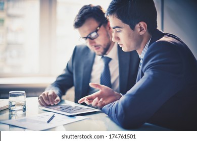 Image of two young businessmen using touchpad at meeting - Shutterstock ID 174761501