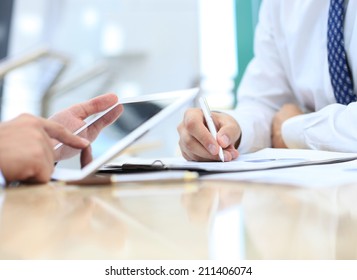 Image of two young businessmen using touchpad at meeting