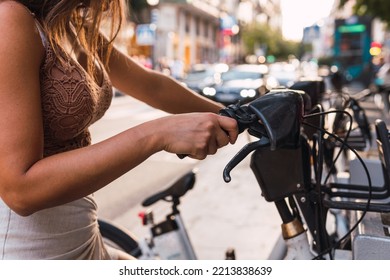 Image Of An Unrecognizable Woman Pulling A Rental Bike Out Of Its Parking Spot In A Big City.