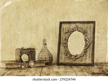 image of victorian vintage antique classical frame and perfume bottles on wooden table. filtered image
